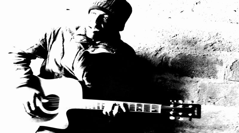 L'artiste camerounais Simon Ngaka avec une guitare acoustique et un bonnet